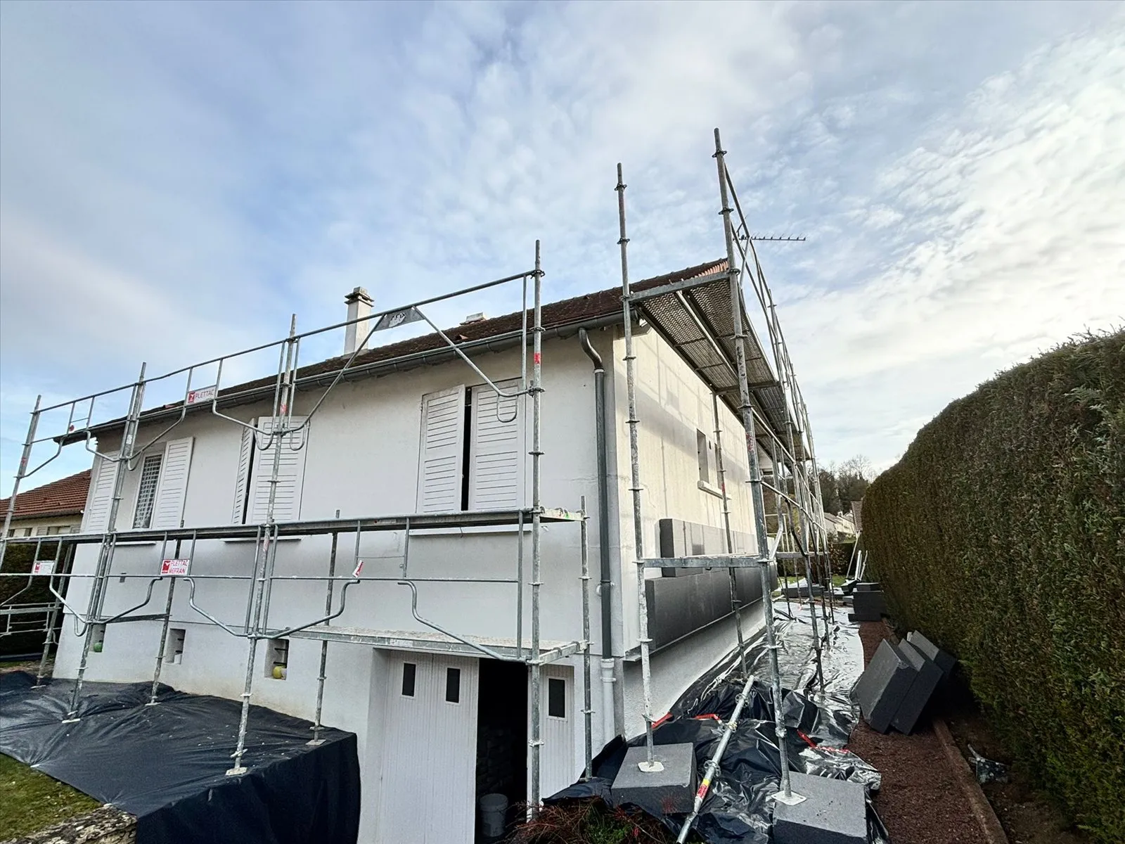 Isolation extérieure : façade blanche achevée sous échafaudage
