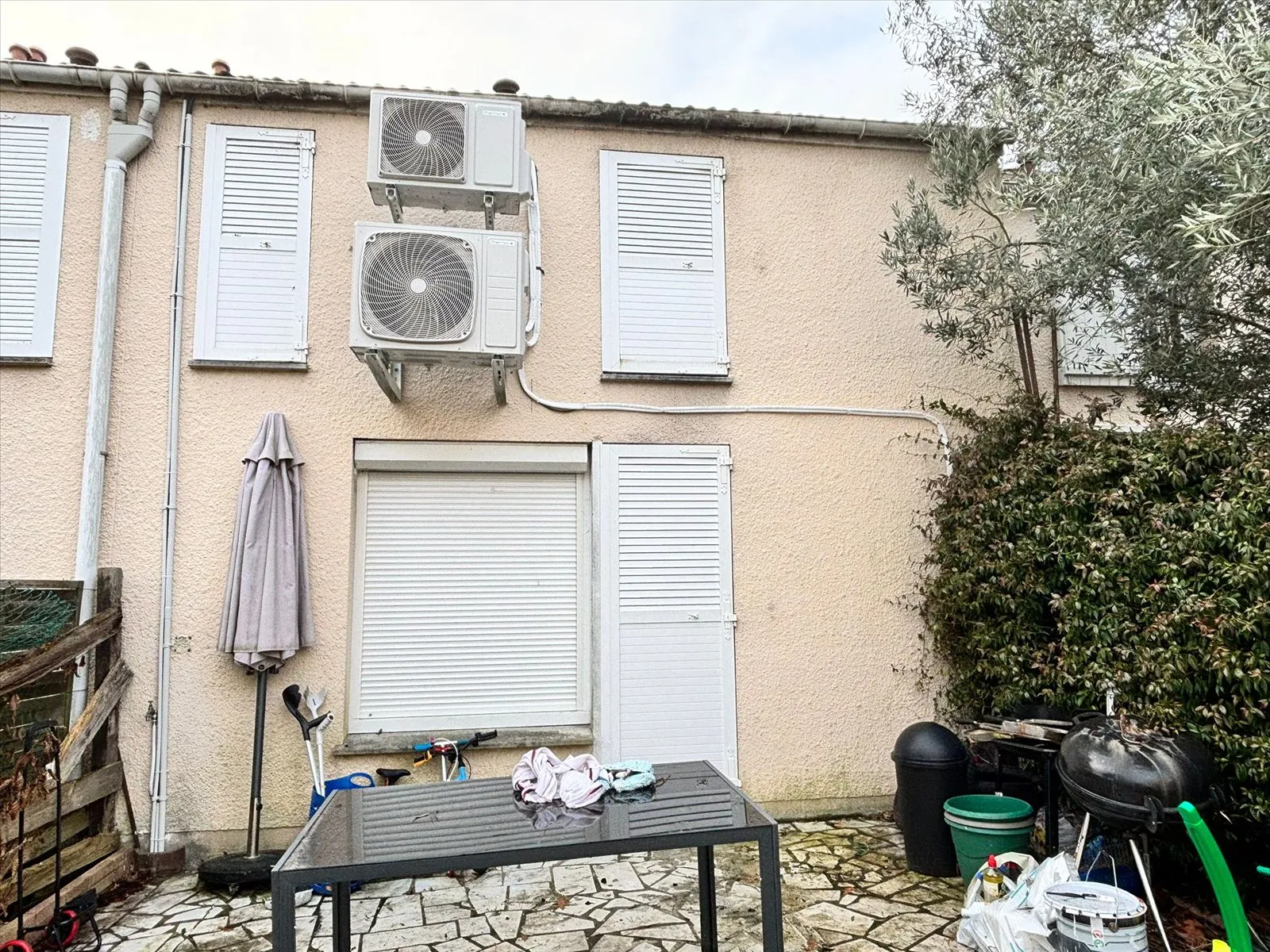 Façade arrière en crépi rose défraîchi, avec deux groupes de climatisation en applique, avant isolation.
