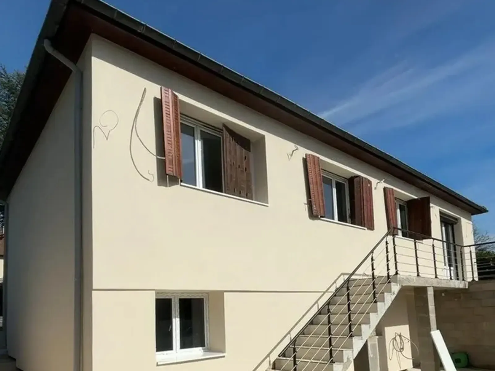 Le même pignon isolé par l'extérieur et enduit, fissures disparues, menuiseries dégagées.
