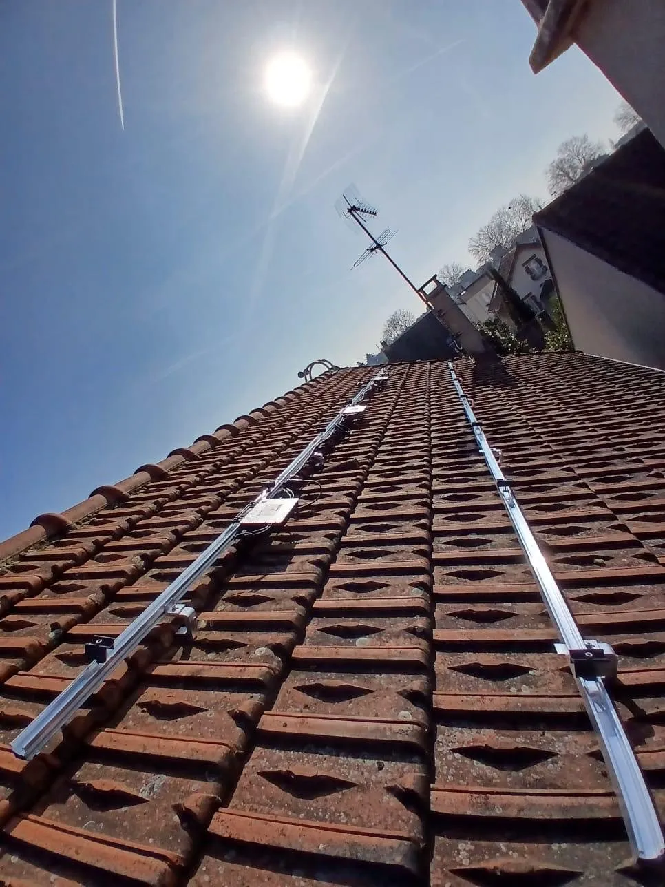 Panneaux solaires : rails de fixation posés sur toiture tuiles, contre-plongée
